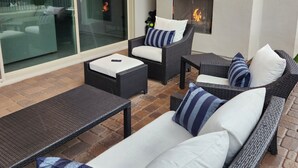 An outdoor patio with wicker furniture, a glass door leading to a view, and a fireplace. - Cave Creek Gem! New Construction! (Cave Creek)