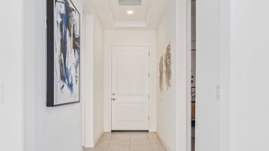 A hallway with a white door, a framed abstract painting, and a decorative wall piece. - Cave Creek Gem! New Construction! (Cave Creek)