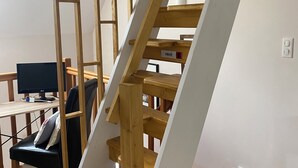 Un escalier en bois, un mur blanc et un bureau avec un ordinateur.