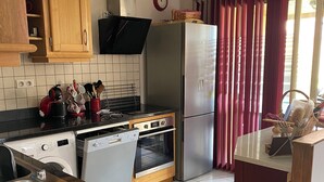 Une cuisine moderne avec des meubles en bois, un réfrigérateur en acier inoxydable, un four encastré et un lave-vaisselle.