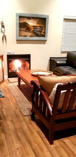 Cozy living room with a fireplace, sofa, and coffee table, featuring a framed picture above the fireplace and a rug on the floor.