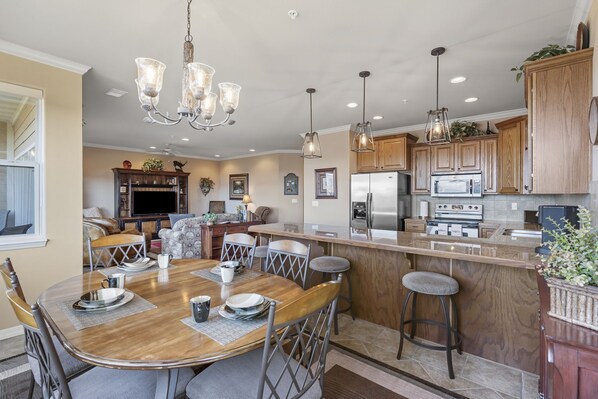 A modern kitchen with wooden cabinets, stainless steel appliances, and a central island with stools.