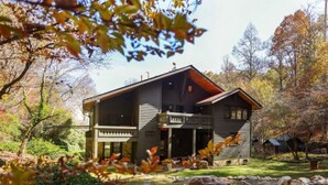 Eine zweistöckige Blockhütte mit Veranda und einem Kiesweg, der zum Eingang führt.