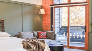 A bedroom with a bed, a sofa, and a sliding glass door leading to an outdoor area. - NEW! Signature Spa Suite with Fireplace & Den (Whittier)