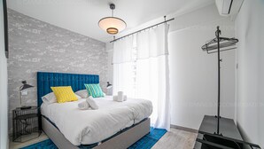 A modern bedroom with a large bed, a blue headboard, and a black side table.