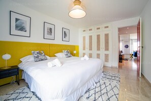 Ein Hotelzimmer mit einem großen Bett, einer gelben Akzentwand, gerahmten Kunstwerken und einer modernen Leuchte.