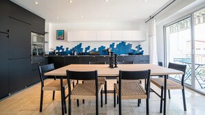 A modern kitchen with a large island, dark cabinetry, and a blue decorative wall.
