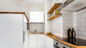 Una cuina moderna amb armaris blancs, un taulell de fusta i una campana extractora d'acer inoxidable.