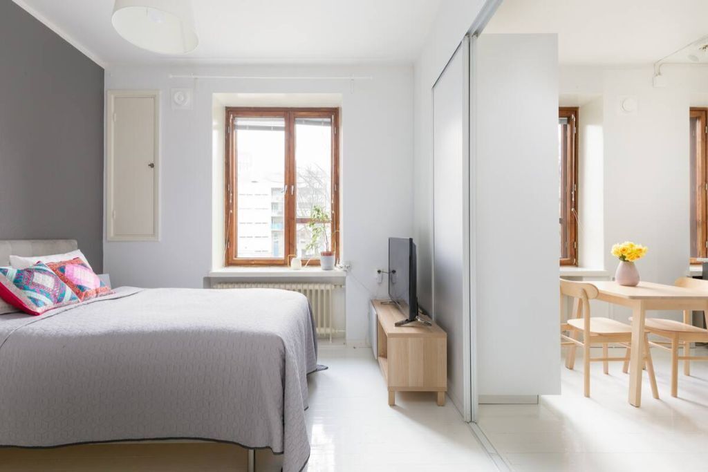 Une chambre à coucher comprenant un lit, une télévision, une fenêtre et un coin repas avec des chaises et une table.