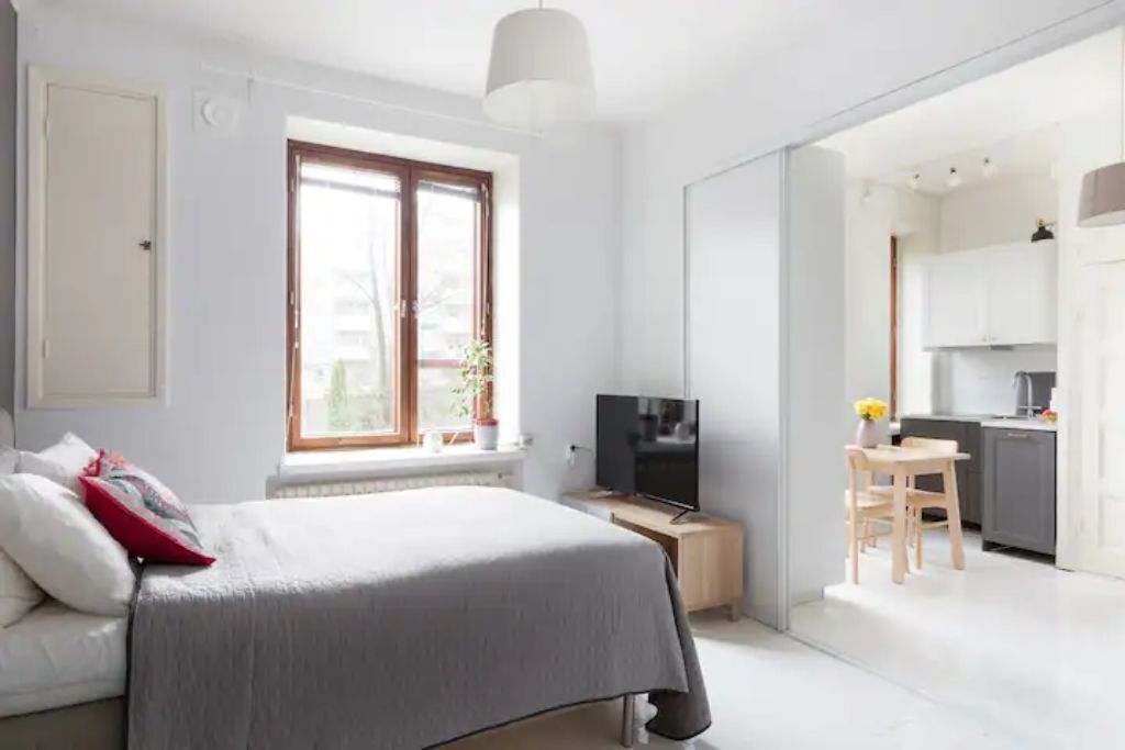 Un dormitorio moderno con una cama, un televisor y una pequeña zona de comedor.