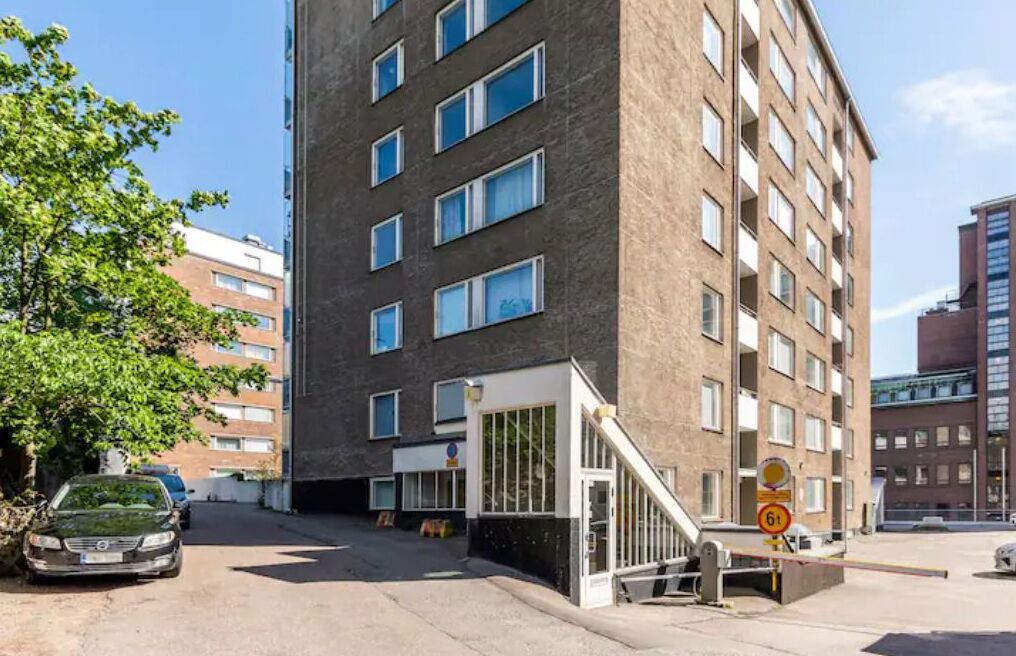 A multi-story building with a modern architectural design, featuring a prominent entrance with a glass facade and a ramp for accessibility.