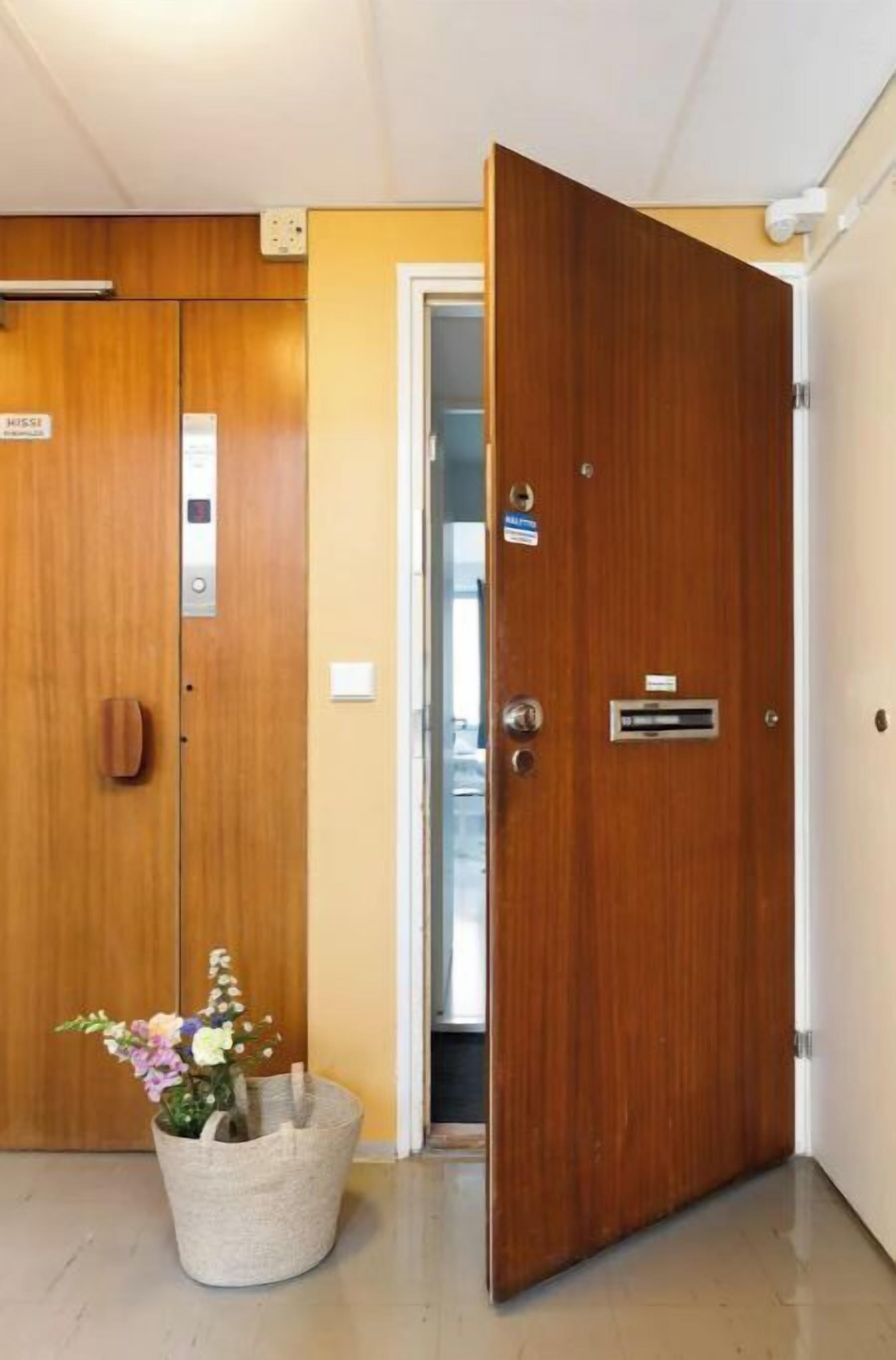Une chambre d’hôtel avec des portes en bois, une poubelle et un petit arrangement floral.