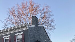 A two-story house with a dark gray exterior, white trim, and a small porch with a chair. - Charming 3-bedroom house in lovely downtown Madison. (Madison)