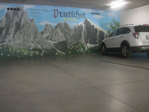 Un parcheggio con un murale raffigurante montagne e fiori sulla parete.
