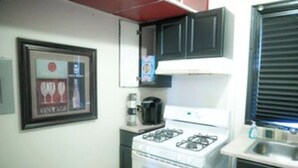 A compact kitchen with a gas stove, a coffee maker, and a framed picture on the wall. - 2BR 1B APT MINS TO DOWNTOWN (Pittsburgh)