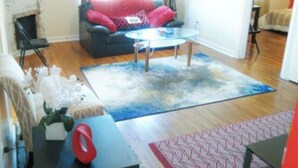 A living room with a dark sofa, a glass coffee table, and a patterned rug. - 2BR 1B APT MINS TO DOWNTOWN (Pittsburgh)