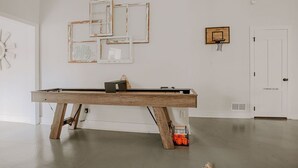 Ein Billardtisch in einem Raum mit weißen Wänden, einem Basketballkorb und einer Tür mit der Aufschrift 'Powder Room'.