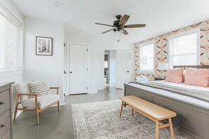 A bedroom with a bed, a bench, a chair, a ceiling fan, and a door. - Afton Clubhouse: Central to Wineries + Hot Tub (Afton)