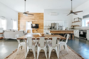 Une cuisine moderne avec des meubles blancs, une table à manger en bois et des chaises blanches.