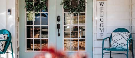 A front door with a 'WELCOME' sign, two windows, and a chair.