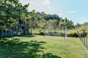 A grassy area with a soccer goal and a rustic building in the background.