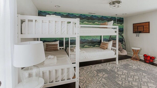 Quarto com beliche, tapete estampado, luminária e cesta de basquete.