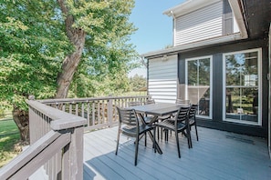 A deck with a table and chairs, overlooking a residential area with trees and houses.