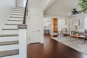 A staircase leading to a powder room, a wooden column, a dining area with chairs, a sofa, and a ceiling fan. - Afton Farmhouse: Central to Wineries/Dog Friendly (Afton)