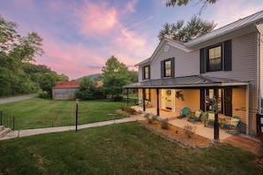 A two-story house with a covered porch, a small shed, and a well-maintained lawn.