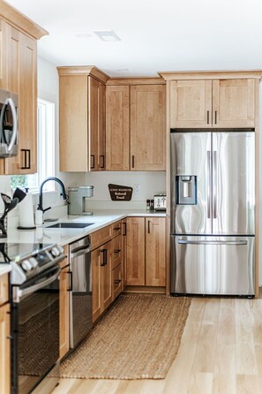 A modern kitchen with wooden cabinets, stainless steel appliances, and a kitchen island. - Fox Hill: Hot Tub, Views, Pet Friendly! (Afton)