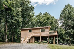 A two-story cabin with a balcony, surrounded by dense forest. - Fox Hill: Hot Tub, Views, Pet Friendly! (Afton)