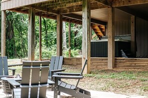 A wooden deck with Adirondack chairs, a grill, and a covered seating area with a view of the forest. - Fox Hill: Hot Tub, Views, Pet Friendly! (Afton)