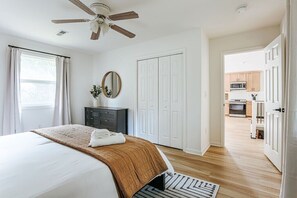 A bedroom with a bed, a ceiling fan, a dresser, a mirror, and a view into the kitchen. - Fox Hill: Hot Tub, Views, Pet Friendly! (Afton)