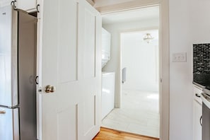Eine Küche mit weißen Schränken, einem Edelstahlkühlschrank und einer schwarzen Arbeitsplatte.