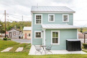 A two-story house with a front porch, a small table, and two chairs.