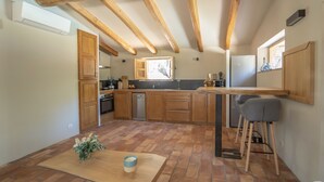Une cuisine avec des poutres en bois, un îlot central et une fenêtre.