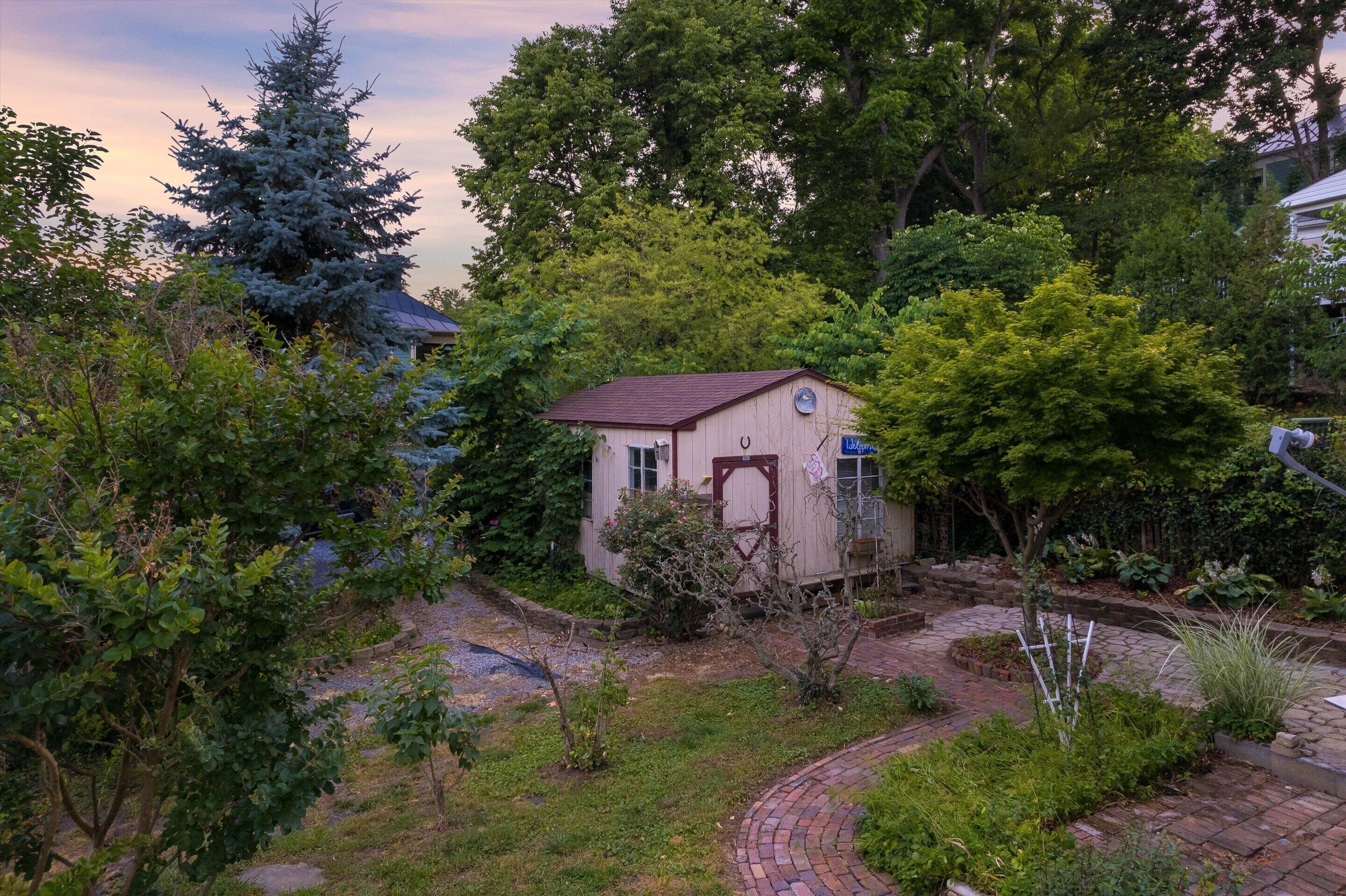 A small house surrounded by lush greenery and a paved pathway.