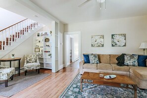 Cozy living area with a staircase, sofa, coffee table, and bookshelf.
