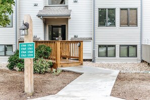 A residential building with a wooden deck and a sign listing apartment numbers. - Panoramic Peak: Wintergreen Condo with Views (Wintergreen Resort)