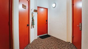 A hallway with three red doors, each marked with the number 1559. A small plant is placed between the middle and right doors. - Panoramic Peak: Wintergreen Condo with Views (Wintergreen Resort)