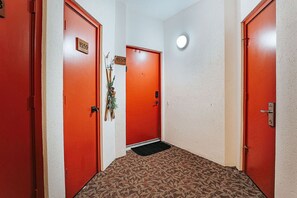 A hallway with three red doors, each marked with the number 1559. A small plant is placed between the middle and right doors. - Panoramic Peak: Wintergreen Condo with Views (Wintergreen Resort)