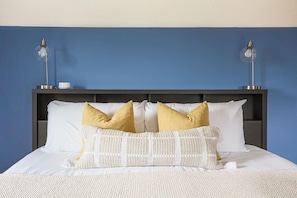 A neatly made bed with white and yellow pillows, a dark headboard, and two bedside lamps. - Ridgeview Retreat: Mountain Views and Pet Friendly (Staunton)