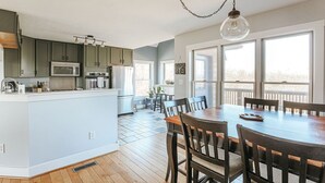 Een moderne keuken met een centraal eiland, houten vloeren en een eethoek met een grote tafel en stoelen.