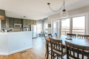 A modern kitchen with a central island, wooden flooring, and a dining area with a large table and chairs. - Ridgeview Retreat: Mountain Views and Pet Friendly (Staunton)