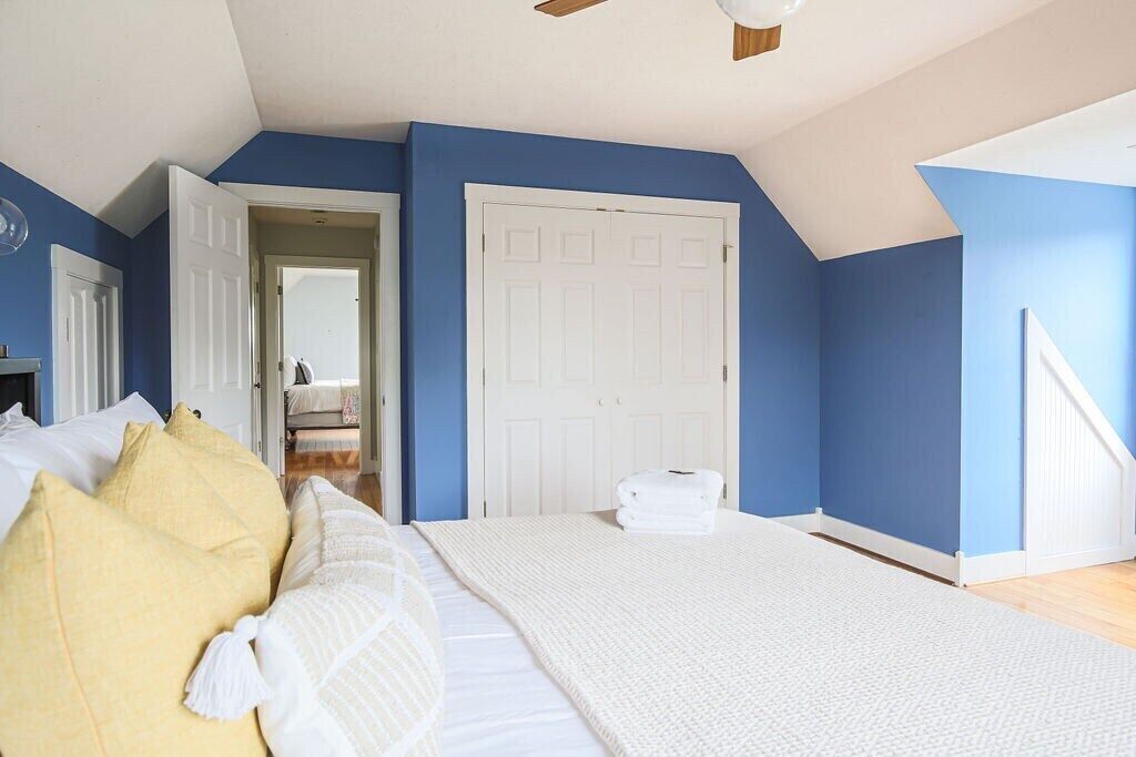 Une chambre avec un grand lit, une porte blanche et un mur bleu.