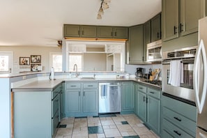 A kitchen with teal cabinets, a stainless steel dishwasher, and a built-in oven. - Ridgeview Retreat: Mountain Views and Pet Friendly (Staunton)