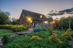 A rustic wooden house with a porch, surrounded by well-maintained gardens and a cross in the yard. - Ridgeview Retreat: Mountain Views and Pet Friendly (Staunton)