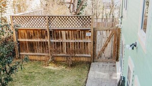 Un cortile con recinzione in legno, vialetto in mattoni e ringhiera bianca.