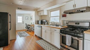 Una cucina moderna con mobili bianchi, un frigorifero nero, un piano cottura e un forno a microonde.