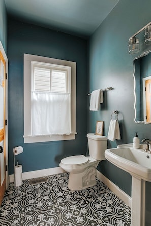 A bathroom with a toilet, sink, and window.